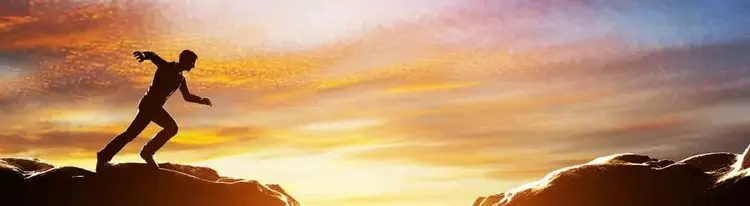 Man poised to run across sunset rocks